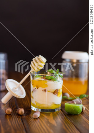 homemade yogurt with kiwi, honey and nuts in a glass on a wooden table 121299453