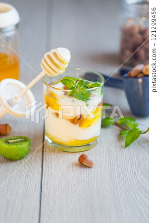 homemade yogurt with kiwi, honey and nuts in a glass on a wooden table 121299456