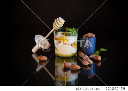 homemade yogurt with kiwi, honey and nuts in a glass, isolated on black background homemade yogurt with kiwi, honey and nuts in a glass, isolated on black background 121299459