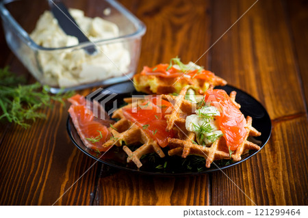 vegetable potato waffles with spread and lightly salted red fish, in a plate on a wooden table 121299464