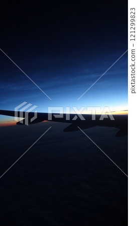 The silhouette of an airplane wing during a flight at sunset 121299823