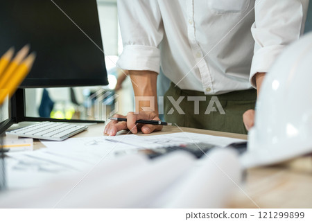 Engineers looking and discussing over blueprints on desk. 121299899