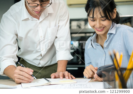Engineers looking and discussing over blueprints on desk. Engineers looking and discussing over blueprints on desk. 121299900