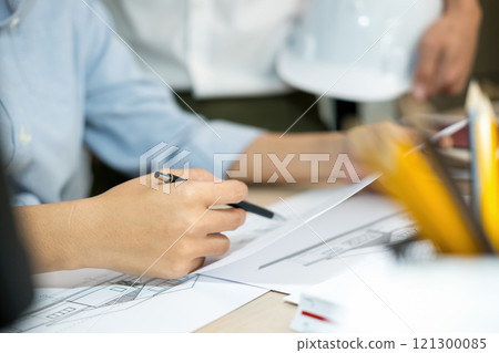 Engineers looking and discussing over blueprints on desk. 121300085