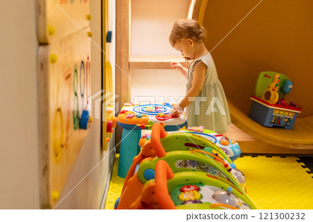 Child interacting with activity table in a sunny playroom. Concept of joyful learning and creativity Child interacting with activity table in a sunny playroom. Concept of joyful learning and creativity 121300232