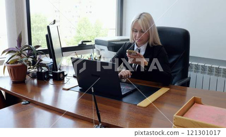 Professional female seated in modern company office using telephone chatting negotiations. In office mid adult woman chat on phone conducting important negotiations modern women in workplace. Professional female seated in modern company office using telephone chatting negotiations. In office mid adult woman chat on phone conducting important negotiations modern women in workplace. 121301017