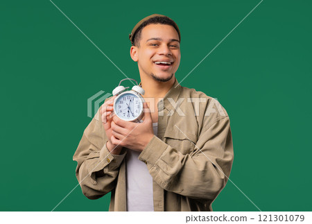Happy man with alarm clock, green background. Early morning, correct day routine 121301079