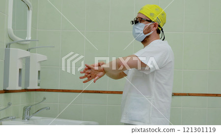 Surgeon meticulously cleans his hands in the hospital restroom before heading into the operating room for a surgical procedure Surgeon meticulously cleans his hands in the hospital restroom before heading into the operating room for a surgical procedure 121301119
