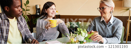 Website header shot of multigenerational team of positive employees and mature female boss chatting over cup of coffee during break in office, copy space Website header shot of multigenerational team of positive employees and mature female boss chatting over cup of coffee during break in office, copy space 121301193