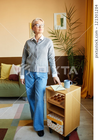 Full length shot of stylish mature woman wearing smart casual outfit confidently posing for photo in modern cozy office with beige walls Full length shot of stylish mature woman wearing smart casual outfit confidently posing for photo in modern cozy office with beige walls 121301284