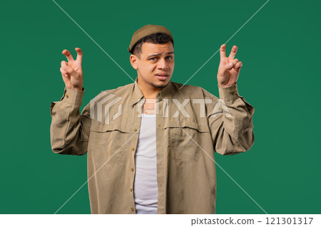 African 30s man with hands two fingers air quotes gesture on green, sarcasm African 30s man with hands two fingers air quotes gesture on green, sarcasm 121301317