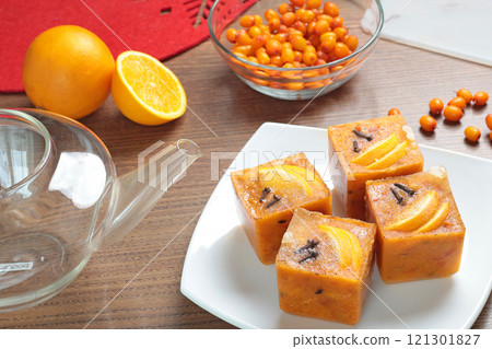 Tea made from frozen briquettes of sea buckthorn, orange and spices in teapot in kitchen. Healthy eating and seasons. Quick beverages to make. 121301827