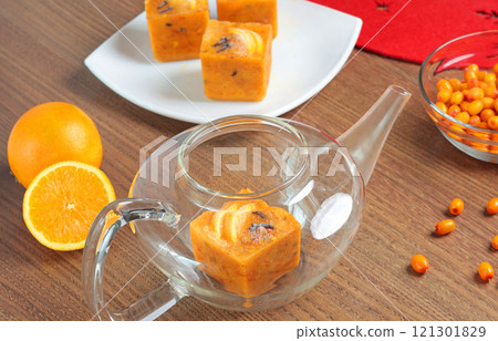 Tea made from frozen briquettes of sea buckthorn, orange and spices in teapot in kitchen. Healthy eating and seasons. Quick beverages to make. 121301829