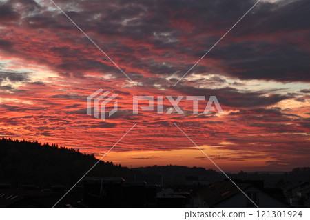 Orange, red sunset over forest and village. Romantic dramatic background for design. Sky and clouds. Orange, red sunset over forest and village. Romantic dramatic background for design. Sky and clouds. 121301924