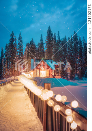 Cozy illuminated wooden lodge with pine forest over frozen Emerald Lake at Yoho national park Cozy illuminated wooden lodge with pine forest over frozen Emerald Lake at Yoho national park 121302178