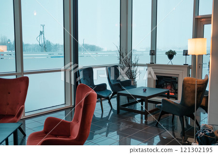 Cozy interior featuring stylish chairs, table and decorate on fireplace 121302195