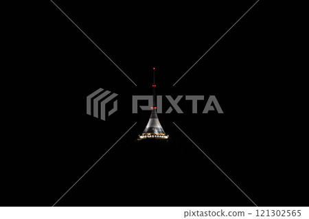 Jested Tower stands elegantly lit against the darkening sky of Liberec, Czechia, showcasing its unique architectural design during the tranquil evening hours. Jested Tower stands elegantly lit against the darkening sky of Liberec, Czechia, showcasing its unique architectural design during the tranquil evening hours. 121302565