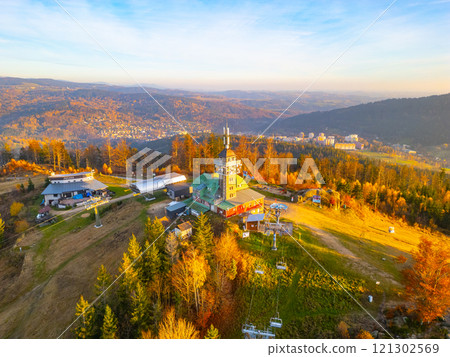 The Tanvaldsky Spicak Lookout Tower stands amidst vibrant autumn foliage in the Jizera Mountains, offering stunning views of the surrounding landscape in the evening light. The Tanvaldsky Spicak Lookout Tower stands amidst vibrant autumn foliage in the Jizera Mountains, offering stunning views of the surrounding landscape in the evening light. 121302569