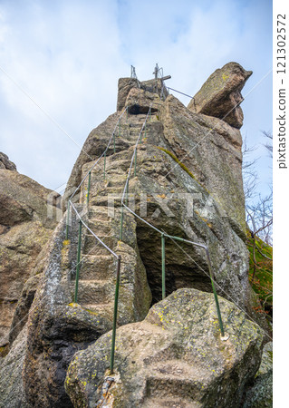 The striking Oresnik granite rock formation features a wooden summit cross and a sturdy lookout point, providing breathtaking views in the Jizera Mountains of Czechia. The striking Oresnik granite rock formation features a wooden summit cross and a sturdy lookout point, providing breathtaking views in the Jizera Mountains of Czechia. 121302572