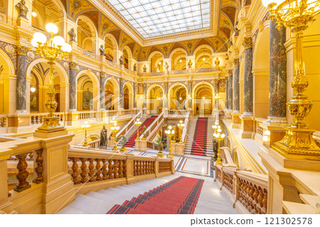The majestic grand staircase at the Prague National Museum showcases intricate architecture and elegant design. Visitors can admire the beautifully crafted details and soft lighting throughout. 121302578