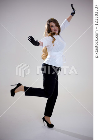Young smiling happy positive cool woman she wears white top shirt casual clothes raise up hands dance have fun isolated on plain pastel light blue cyan background studio portrait. Lifestyle concept 121303337