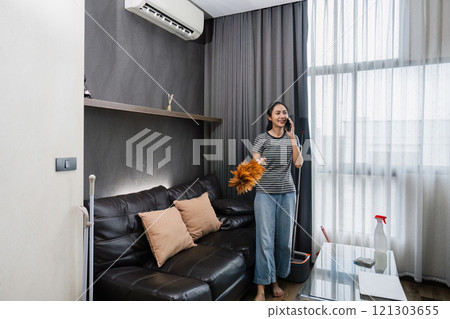 Young woman chit chat with friend on mobile while cleaning house on weekend Young woman chit chat with friend on mobile while cleaning house on weekend 121303655