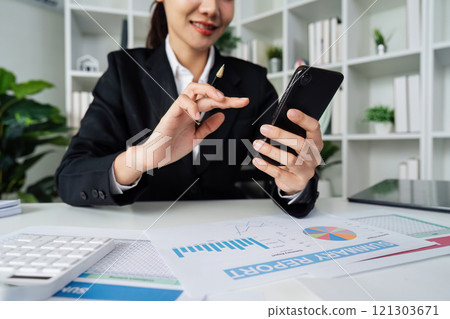 business woman using smartphone while working on laptop, synchronize data between computer and gadget at home, use corporate devices and business application business woman using smartphone while working on laptop, synchronize data between computer and gadget at home, use corporate devices and business application 121303671