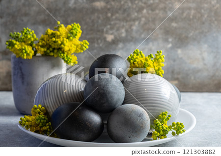 Black Easter eggs Elegant Ceramic Spheres with Yellow Flowers on Table 121303882