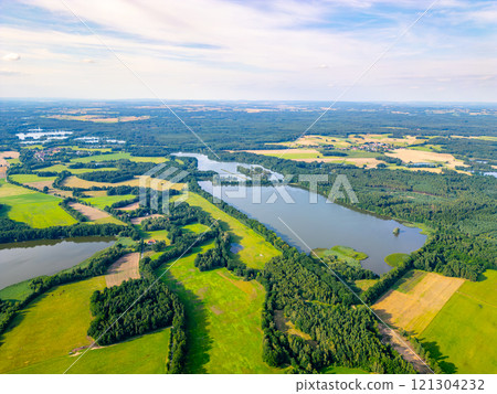 Surrounded by lush greenery and shimmering water, the landscape of Trebon showcases a harmonious blend of fields and forests, reflecting the beauty of rural Czechia in a stunning aerial perspective. 121304232