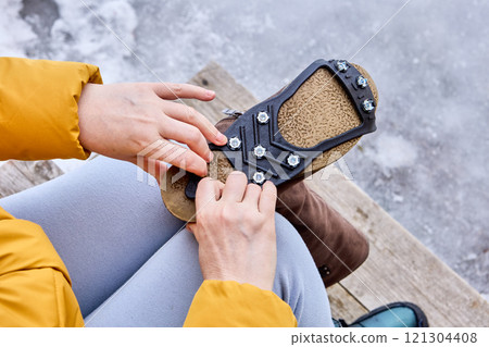 Rubber lining with spikes is stretched onto sole of winter boot to improve traction and prevent slipping. 121304408