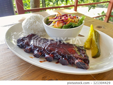 caramelized fried BBQ beef ribs with vegetable salad, rice and pickled cucumbers caramelized fried BBQ beef ribs with vegetable salad, rice and pickled cucumbers 121304429