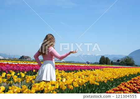 beautiful happy woman in a field of pink tulips smiling 121304555