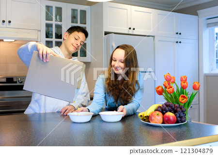 Young woman preparing muesli for breakfast in her kitchen, morning routine and healthy lifestyle concept. 121304879