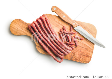 Smoked kabanos. Mini dried thin sausages on cutting board isolated on white background Smoked kabanos. Mini dried thin sausages on cutting board isolated on white background 121304990