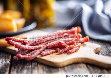 Smoked kabanos. Mini dried thin sausages on cutting board on wooden table. 121305000