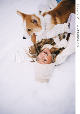 Happy young woman playing with her welsh corgi pembroke puppy, winter forest 121305645