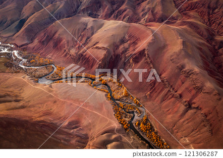 Aerial view of Mars-like red hills with river winding through unique valley 121306287