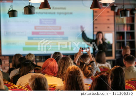 Audience attentively listens to a presenter during a business conference Audience attentively listens to a presenter during a business conference 121306350