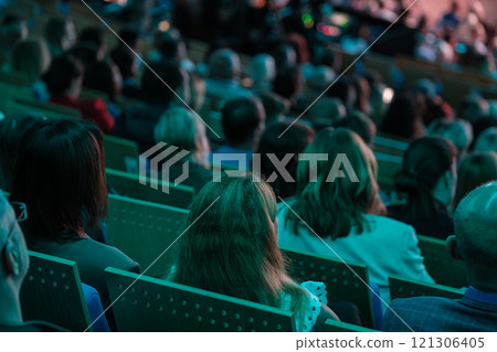 Audience attending a presentation seminar with focus on attendees seated in chairs 121306405