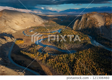 Aerial view of meandering river through forested and mountainous autumn landscape 121306460