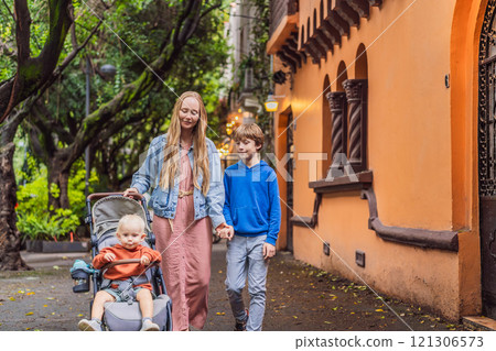 Mother with her two sons exploring lush streets of Condesa, Mexico City. Family adventure in a vibrant urban oasis. Travel, family bonding, and urban greenery concept in Latin America Mother with her two sons exploring lush streets of Condesa, Mexico City. Family adventure in a vibrant urban oasis. Travel, family bonding, and urban greenery concept in Latin America 121306573