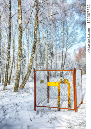 View on old yellow gas pipe with a crane in a winter park. View on old yellow gas pipe with a crane in a winter park. 121307762