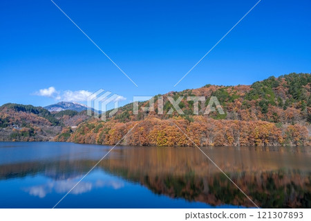 Lake Mitake and Mt. Mitake surrounded by colorful autumn leaves against a blue sky Lake Mitake and Mt. Mitake surrounded by colorful autumn leaves against a blue sky 121307893