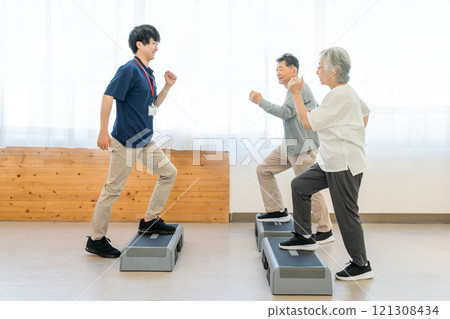 Senior men and women training at a day service/personal gym and a young male instructor Senior men and women training at a day service/personal gym and a young male instructor 121308434