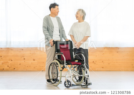 Senior couple talking in front of a wheelchair 121308786