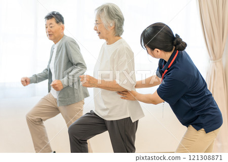 在日間服務中鍛鍊的老年男性和女性以及擔任物理治療師、職業治療師和護理經理的女性 在日間服務中鍛鍊的老年男性和女性以及擔任物理治療師、職業治療師和護理經理的女性 121308871