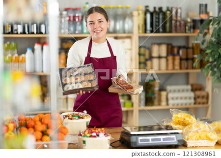 Young woman seller offering sweets in grocery store 121308961