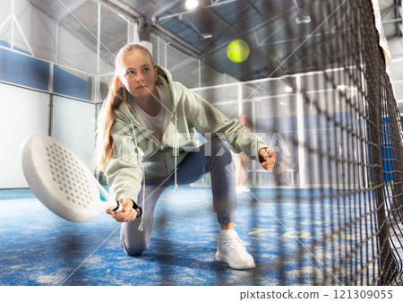 Teenager girl plays paddle. View through grid 121309055