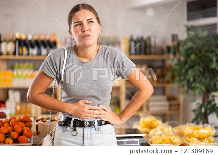 Woman in the store holding her stomach 121309169