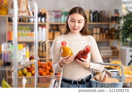 Young woman choose consider juice in store Young woman choose consider juice in store 121309270